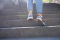 Woman legs in jeans and sneakers going up steep stairs Royalty Free Stock Photo