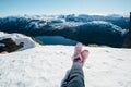 Woman legs in pink boots. Woman sitting on the snow. Scenic landscape of river channel, sea between rocky shore with