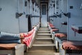 Woman legs in red tennis shoes in a vintage empty train car. Fem