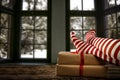 Woman legs in red and white christmas stockings and christmas presents on wooden table, snowy winter outside the window background Royalty Free Stock Photo