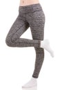 Woman legs from the side in grey sports thermal pants standing on one leg with other leg raised in white socks