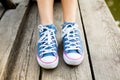 Woman legs in sneakers on a wood