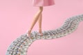 Woman legs walk along a money path, dollar bills road on pink background Royalty Free Stock Photo