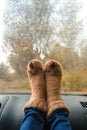 Woman legs in warm cute socks on car dashboard. Drinking warm tee on the way. Fall trip. Rain drops on windshield. Freedom travel Royalty Free Stock Photo