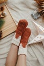 Woman legs in warm socks on soft blanket with christmas star, trees and candle, top view. Cozy moments at home. Winter and autumn