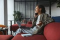 Woman sitting comfortably on a couch with a laptop, talking on a cell phone in nice modern coworking office Royalty Free Stock Photo