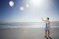 Woman Letting Go Of Balloons On Beach