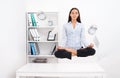 Woman levitating above office desk and meditating in lotos position