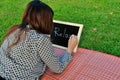 Woman lie down on grass and write on blackboard