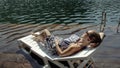 Woman lie on a sunbed in sunglasses and a boho silk shawl. Girl rest on a flood wood underwater pier. The pavement is