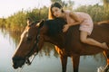 Woman lies astride a horse at river