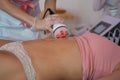 A woman lies on a couch in a beauty salon. Anti-cellulite massage of the female abdomen using the apparatus. Hardware Royalty Free Stock Photo