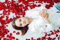 a beautiful woman lies in the flowers of the petals of red roses Royalty Free Stock Photo