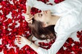 a beautiful woman lies in the flowers of the petals of red roses Royalty Free Stock Photo