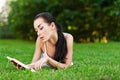 Woman lies on grass and reads book