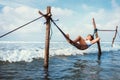 Woman lies in hammock over the waves and enjoy with sun light