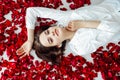 beautiful woman lies in the petals of a red rose Royalty Free Stock Photo