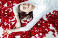 beautiful woman lies in the petals of a red rose Royalty Free Stock Photo