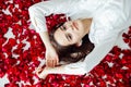 beautiful woman lies in the petals of a red rose Royalty Free Stock Photo