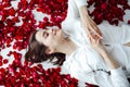 beautiful woman lies in the petals of a red rose Royalty Free Stock Photo