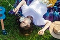 Woman lies on a purple blanket. On her body is a bouquet of daisies. Meditative state in a public park. On background of the