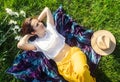 Woman lies on a purple blanket. On her body is a bouquet of daisies. Meditative state in a public park. On background of the