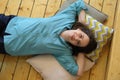 Woman lies on wooden floor and smiles. Moment of rest and relaxation of a girl in a good mood Royalty Free Stock Photo