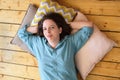 Woman lies on wooden floor and smiles. Moment of rest and relaxation of a girl in a good mood Royalty Free Stock Photo