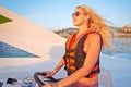 Woman in life-jacket stands at helm of motorboat