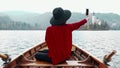 Pretty young girl sitting in boat and taking selfie on mobile phone at background of the Alph mountain view. Happy asian