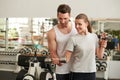 Woman lifting dumbbell with her trainer. Royalty Free Stock Photo