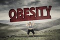 Woman lifting obesity word in hills