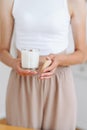 Woman in Light Clothes Holds Soy Candle in her Hands in Glass and Wooden Lid