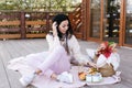 woman in light clothes and white sneakers sits on a plaid