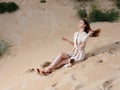 A woman in a light dress and red sandals on the sand on the beach near the sea Royalty Free Stock Photo