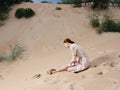 A woman in a light dress and red sandals on the sand on the beach near the sea Royalty Free Stock Photo