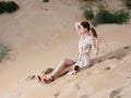 A woman in a light dress and red sandals on the sand on the beach near the sea Royalty Free Stock Photo