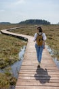 woman in a light shirt and jeans walking on a wooden path in nature Royalty Free Stock Photo