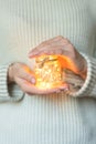 Woman in a light warm wool sweater holding a holiday led light garland in a glass in her hands, concept of warmth, holiday, copy s