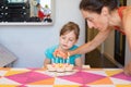 Woman lighting candles on birthday cake and child looking Royalty Free Stock Photo