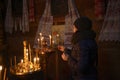 Woman lighting candles praying in front of icons in Ukrainian Orthodox rural church. Pyrogove, Ukraine
