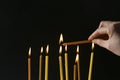 Woman lighting church candle on black background, closeup