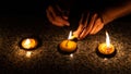 A woman is lighting three Thai styled candles during Loy Krathong or Yeepeng festival in Chiang Mai