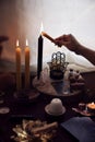 A woman lights a black candle on her witch altar to perform an esoteric ritual
