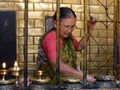 A woman lights candles inside Hiranya Varna Mahavihar. Golden Temple. Patan, Kathmandu. Nepal