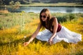 Woman like a fairy on the magic field near the river. Young woman with dandelion. Fantasy style