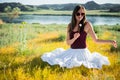 Woman like a fairy on the magic field near the river. Young woman with dandelion. Fantasy style