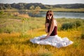 Woman like a fairy on the magic field near the river. Young woman with dandelion. Fantasy style