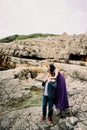 Woman in a lilac dress hugs man from behind standing on the rocks Royalty Free Stock Photo
