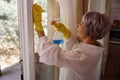 Woman with lilac hair washes a window with yellow rag